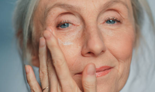 Mature woman applying anti-aging skincare around eyes, representing beauty routines for women in menopause.