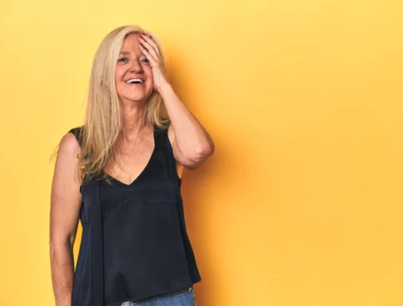Cheerful woman in her late 40s laughing, showing natural beauty, joy, and confidence in midlife despite having menopause symptoms.