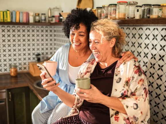 Two Midlife women sharing coffee and laughing, representing friendship, support, and joyful connection for women over 40.